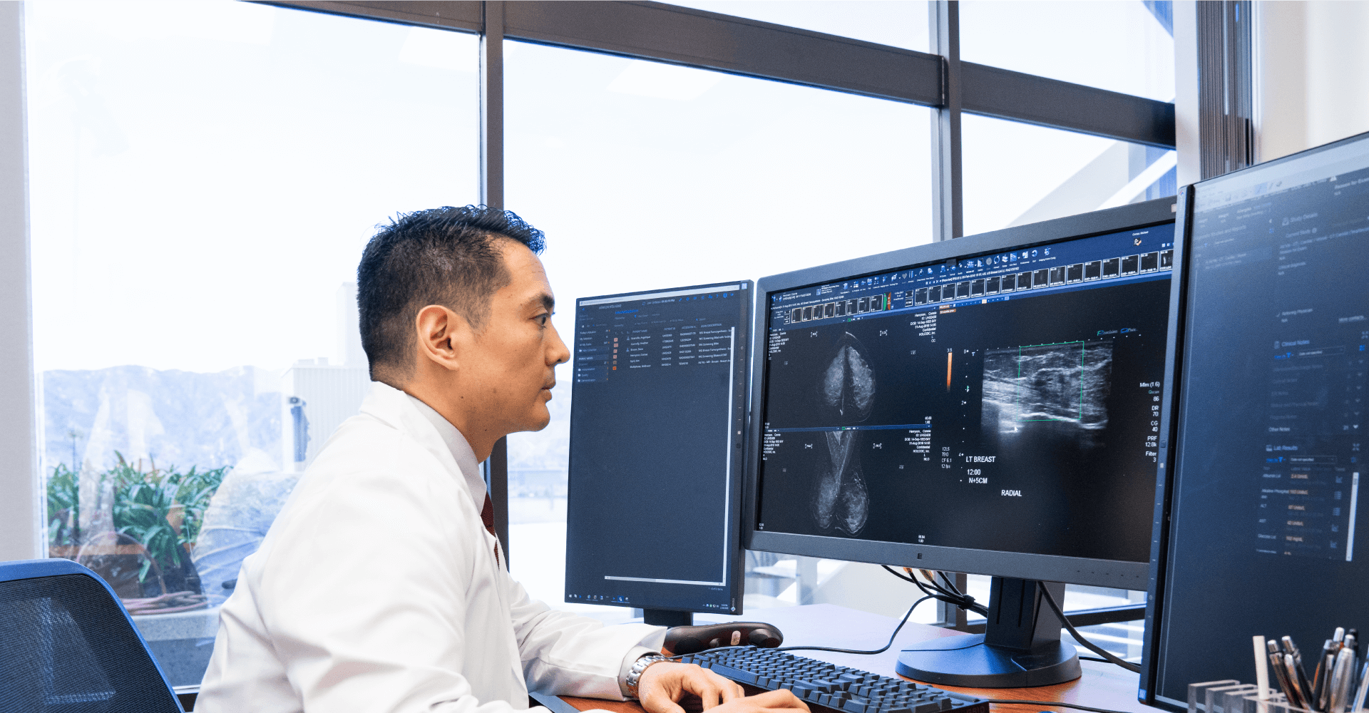 Doctor looking at images on 3 computer screens
